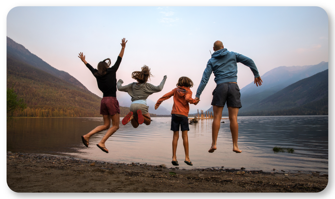 family jumping on beach at lake