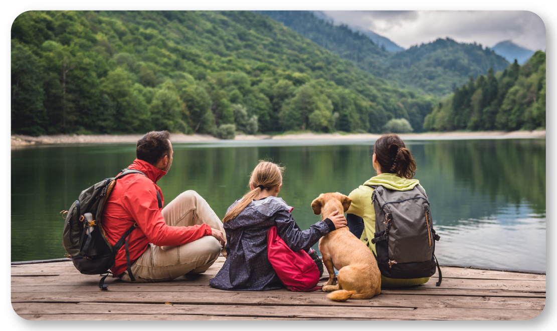  family of three and a dog sitting on a dock at a lake